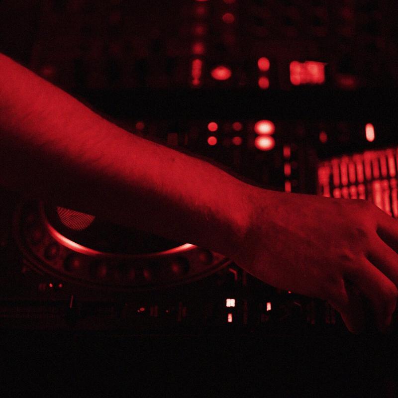 Karanlık DJ kabininde ışıklı mikser ve ekranlar