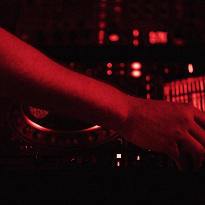 Karanlık DJ kabininde ışıklı mikser ve ekranlar
